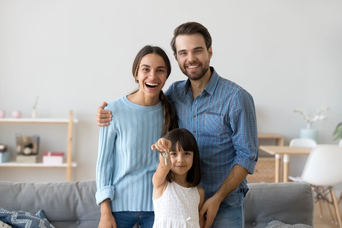 A man and woman holding a child in front of a couch.