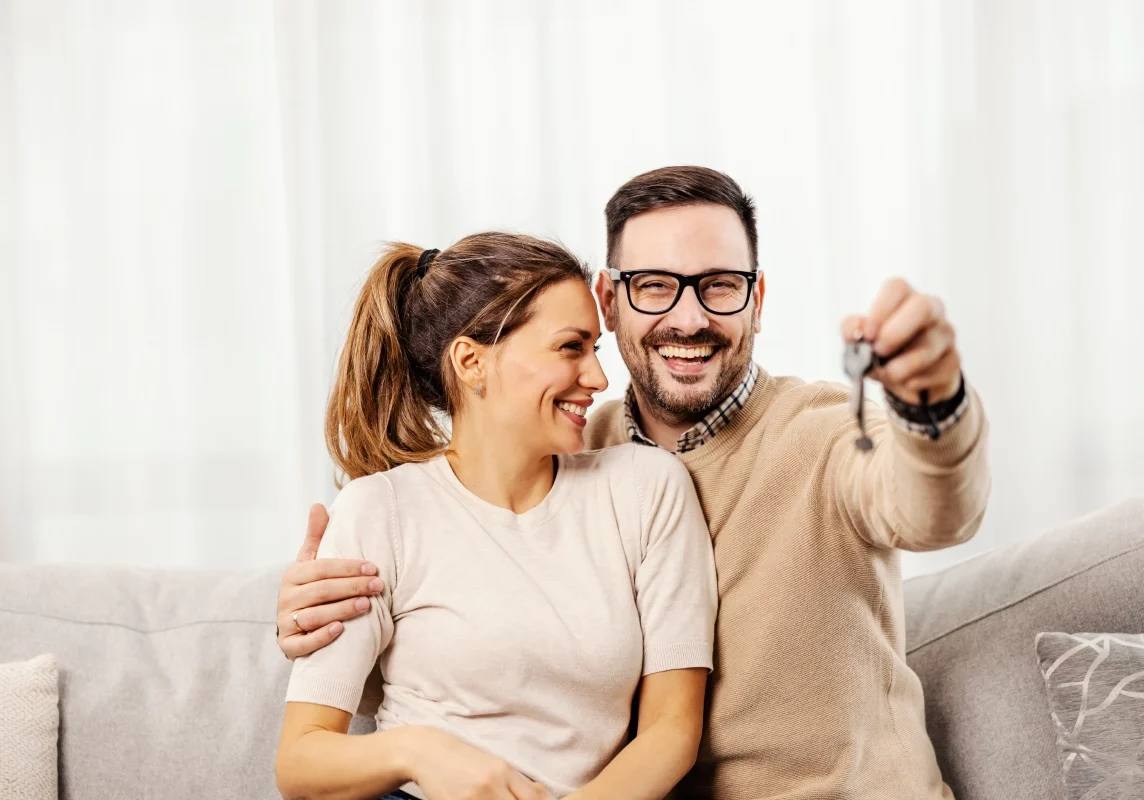 A man and woman sitting on the couch holding keys.